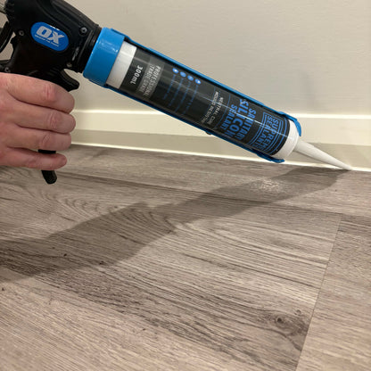 Applying Supreme Sealants sanitary silicone along a skirting board with a caulking gun